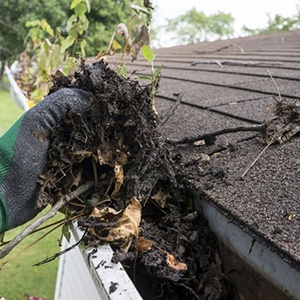 person cleaning gutters using gutter cleaning tools